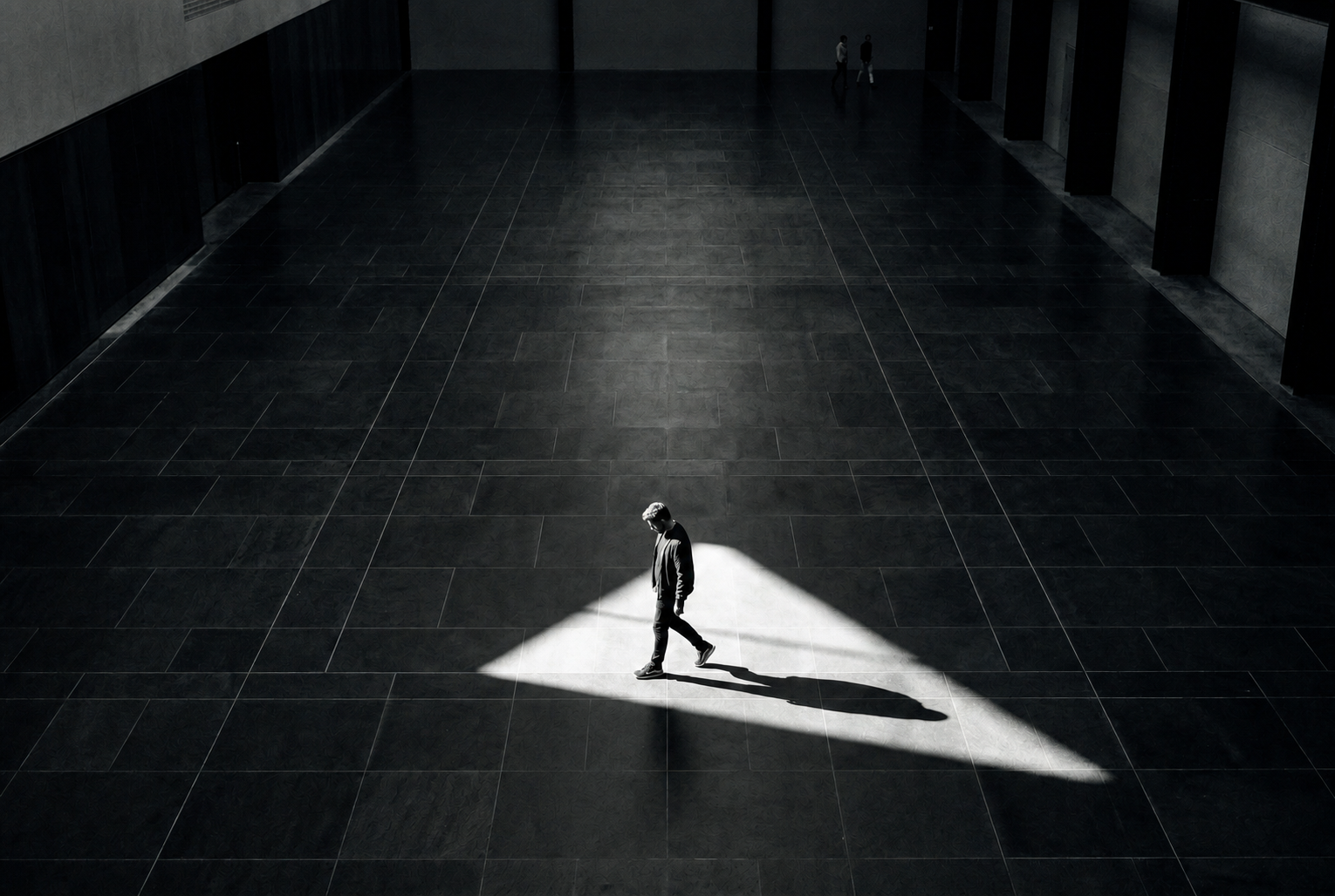 Pessoa atravessando um feixe de luz em uma arquitetura monumental